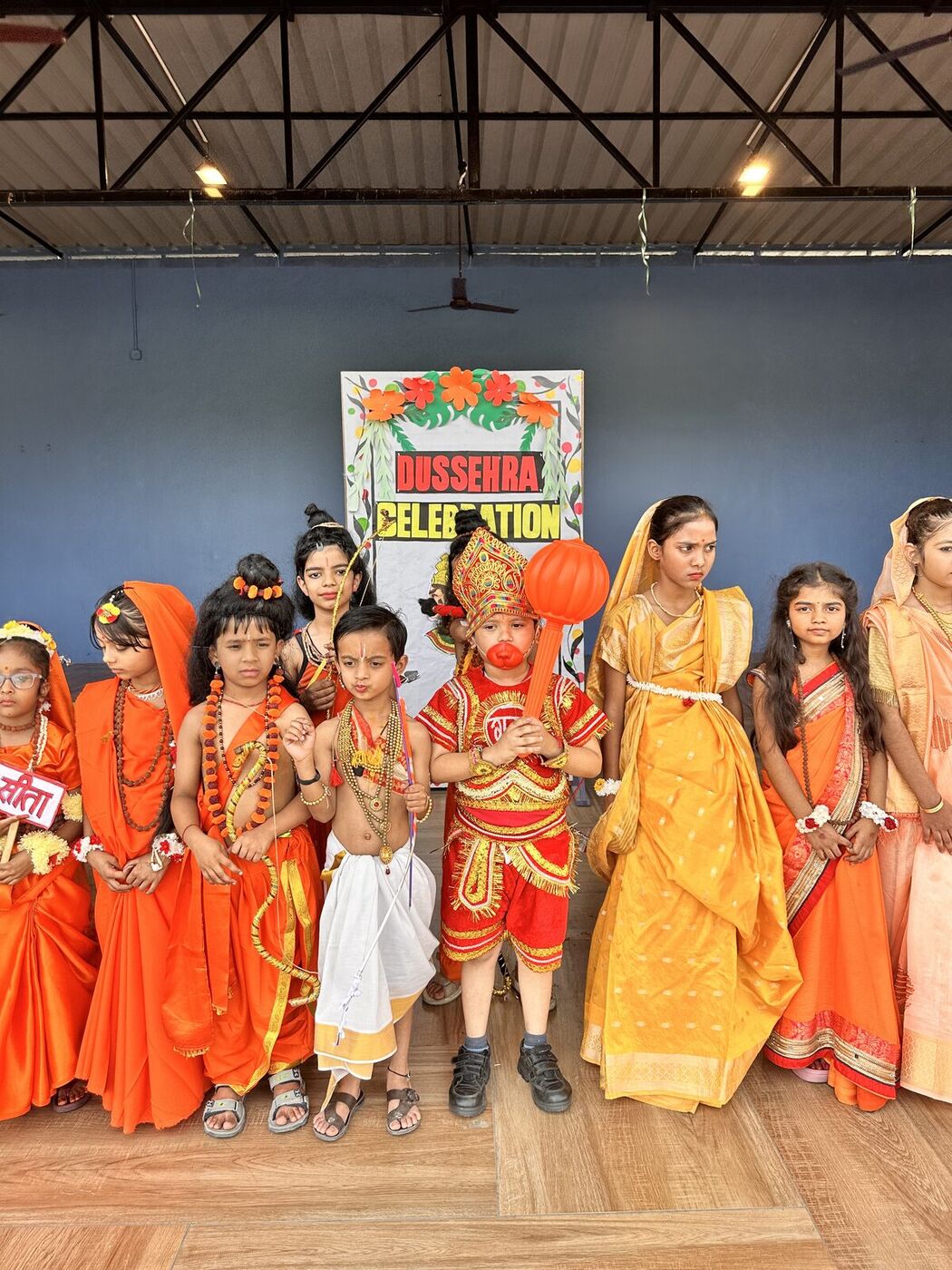 A group of costumed students in front of the Dussehra Celebration banner