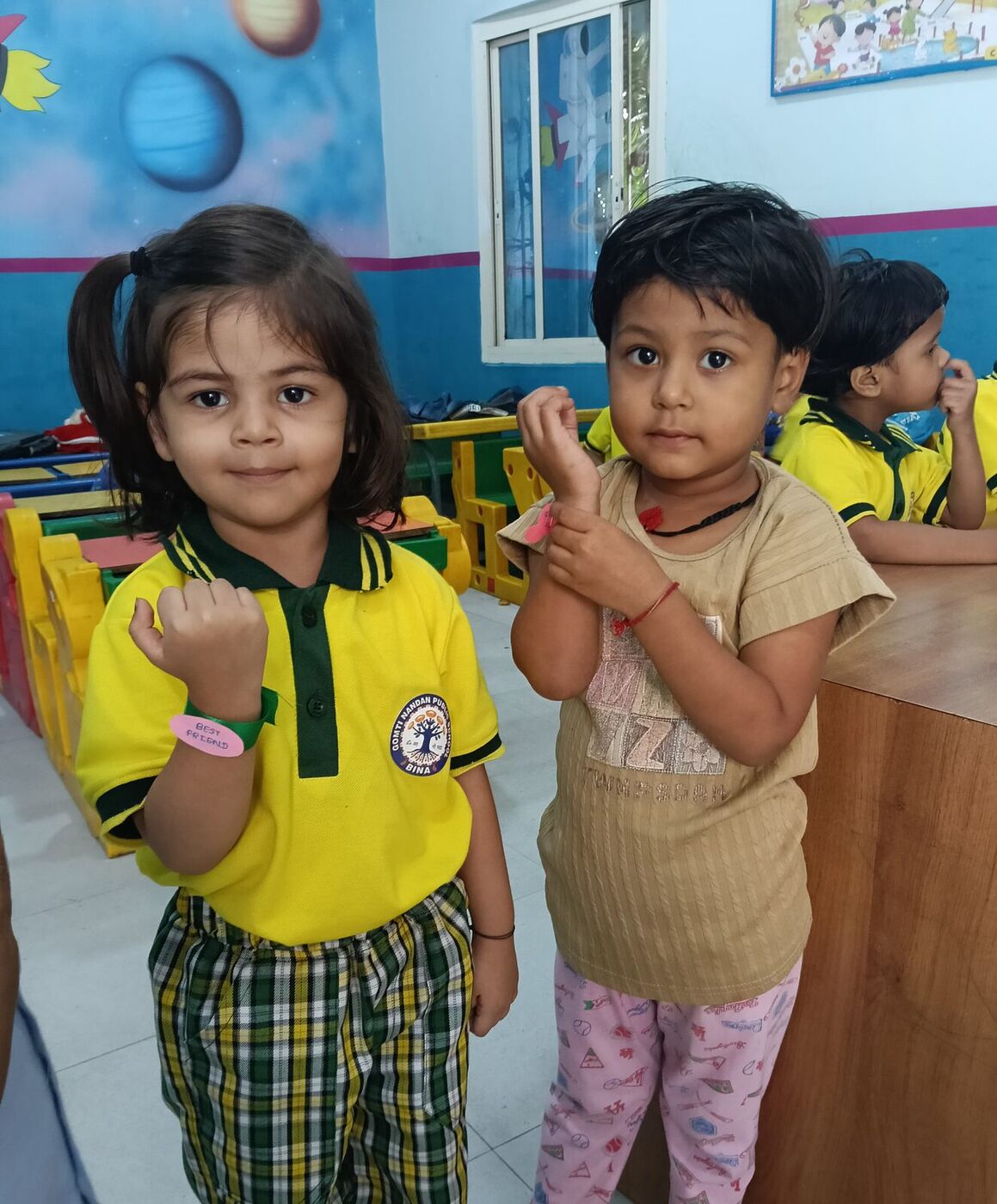 Two young friends show off their friendship bands