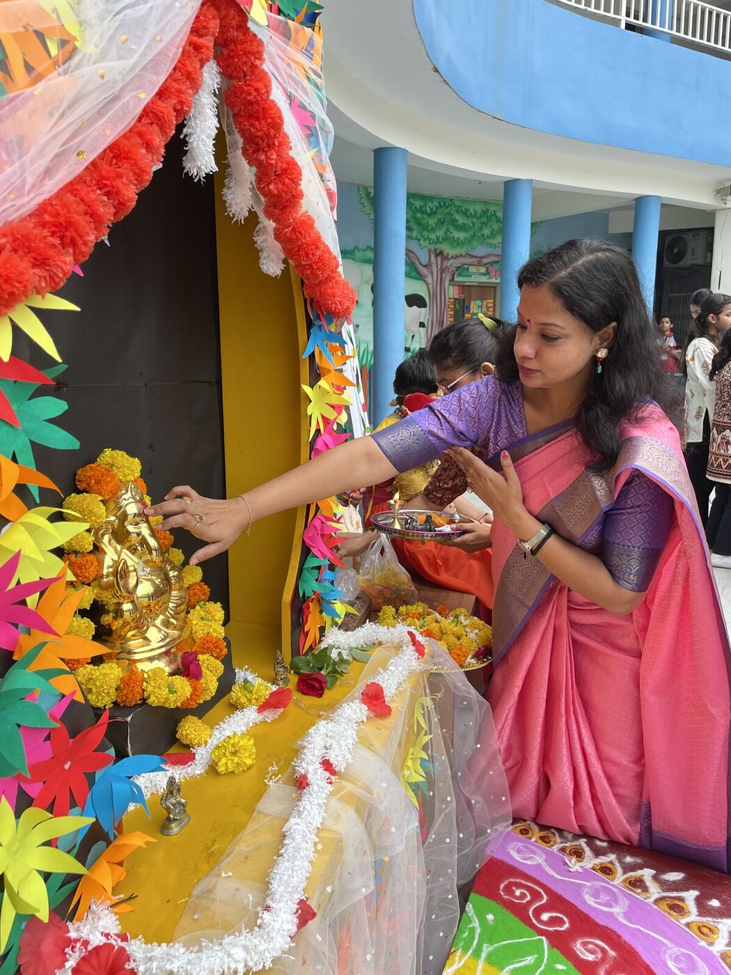 A teacher offers prayers at the decorated Ganesha shrine