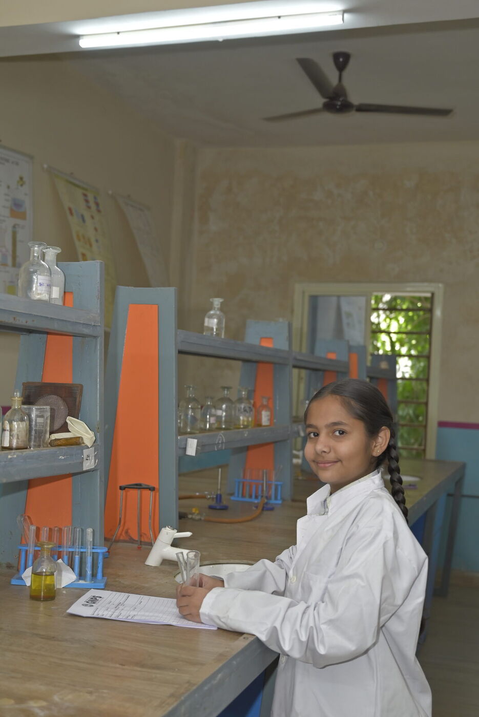 A student smiles while working at the science lab bench