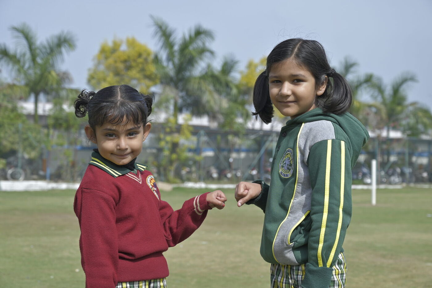 Two young friends share a fist bump on the school lawn
