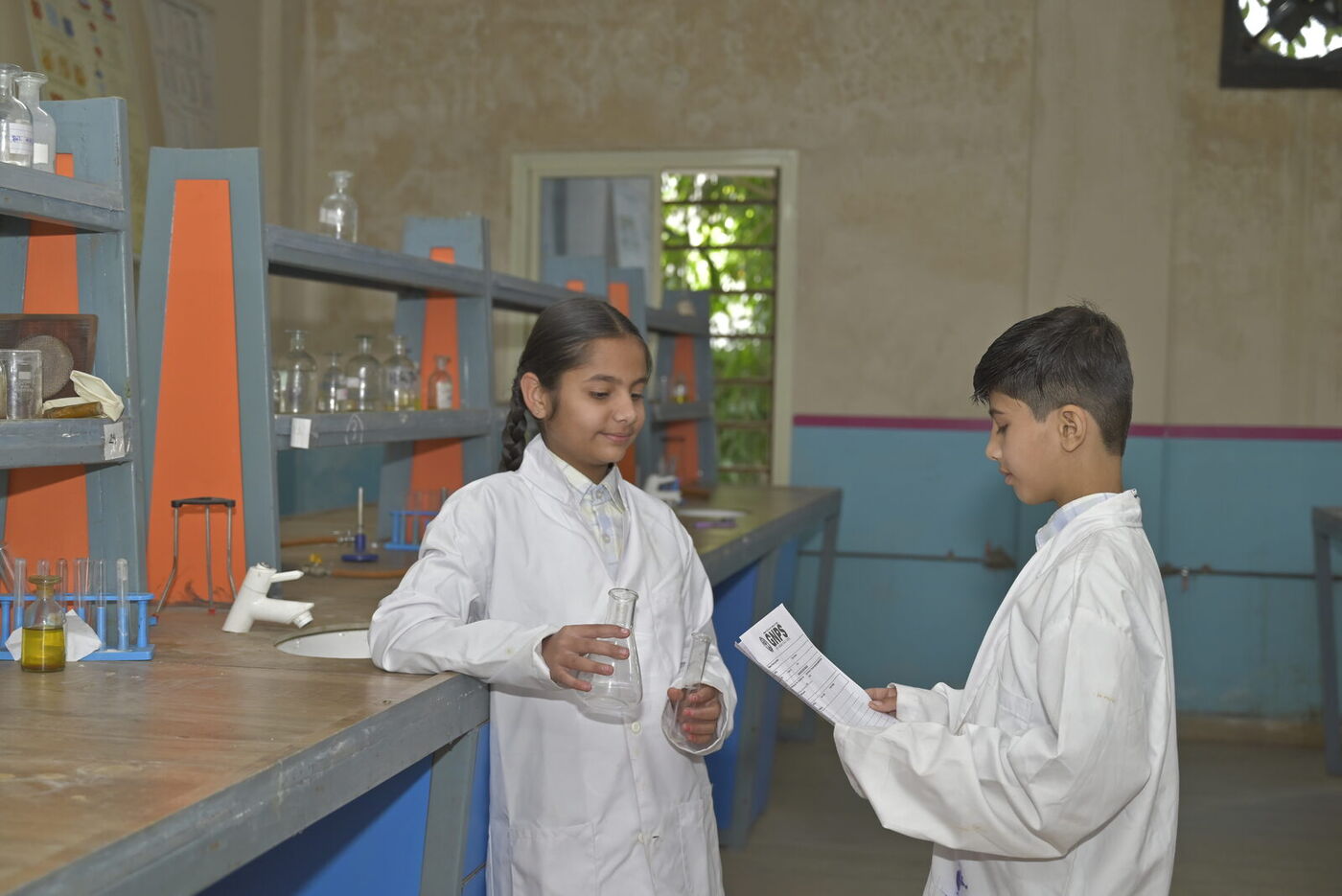Two students in lab coats carry out an experiment in the science lab